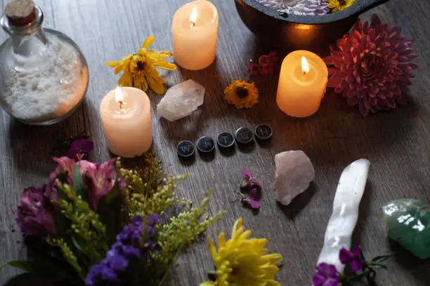 A Green Witch Altar space with flowers, cauldron, candles, crystals, and salt.