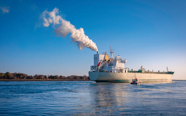 istock Large Steam Ship Passing through Cape Cod Canal. Cargo Carrier and Pilot Ship over the Cape Cod Bay Entrance. Blue Sky and Water with White Steam Trails. 1310823730