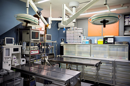 Unoccupied surgical suite with operating tables, lights, and medical technical equipment.