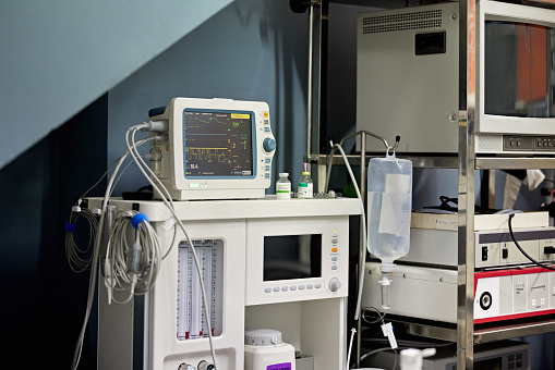 Electronic monitors, IV fluid bag, and other equipment for patient in animal hospital operating room.