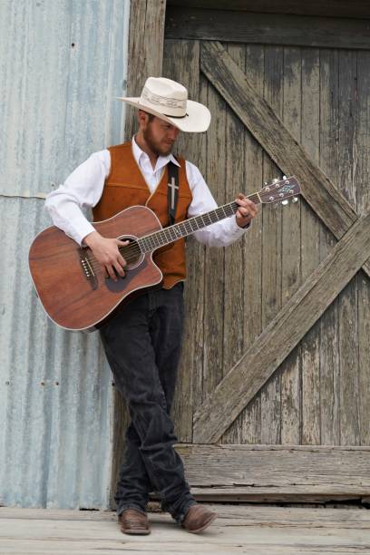 istock Cowboy Plays Guitar by Rustic Barn Door 1310830308