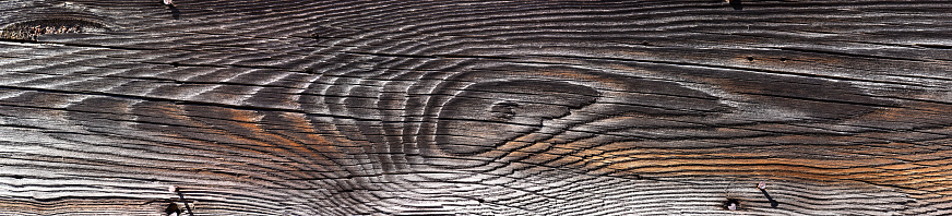 Very weathered wood grain from a plank of wood on the side of a very old farm house.