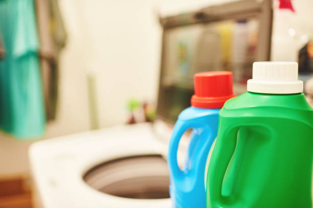 garrafa de detergente de lavanderia na frente da máquina de lavar em uma lavanderia doméstica - chemical bottle cap chores - fotografias e filmes do acervo