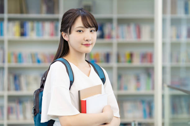 studentessa asiatica in piedi in biblioteca. - japanese ethnicity college student student asian ethnicity foto e immagini stock