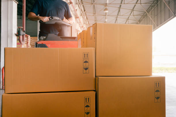 istock Stack of Package Boxes at the Warehouse. Woker Driving Forklift Pallet Jack. Shipment Boxes. 1310847229
