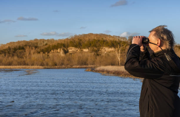 istock Senior man with binoculars watching birds in Missouri floodplain 1310853239