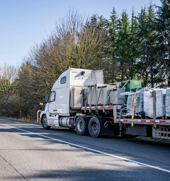 istock Loaded big rig semi truck with secured with slings cargo on step down semi trailer standing on the road shoulder out of service waiting for mobile repair help 1310855608