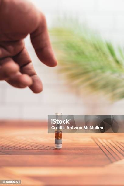A Hand Reaches To Pick Up A Cannabis Vaporizer Cartridge Stock Photo - Download Image Now