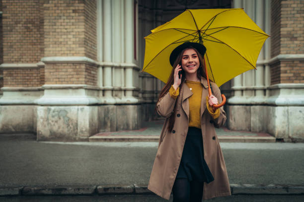 istock Woman with yellow umbrella using smartphone 1310859103
