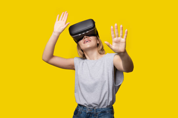 istock Modern blonde woman wearing a virtual reality headset smiling on a yellow studio wall 1310865866