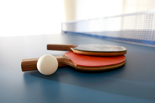 Red And Dark Blue Rackets Stand On The Table Tennis Table
