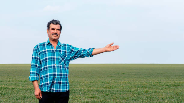 istock Experienced and confident farmer stands on his field with hand outstretched. 1310871696