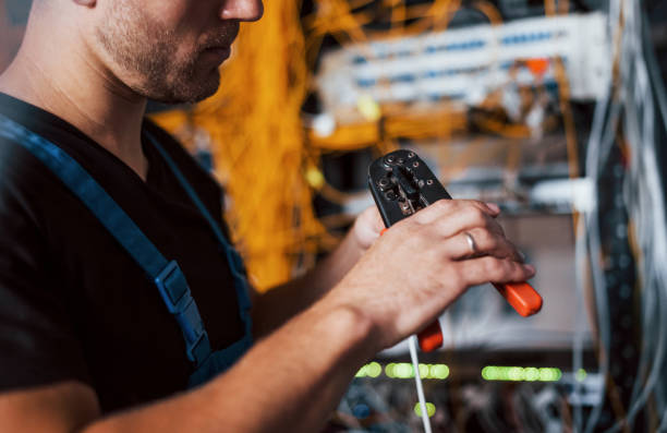 istock Young man in uniform works with internet equipment and wires in server room 1310873094