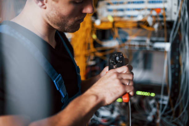 istock Young man in uniform works with internet equipment and wires in server room 1310873116