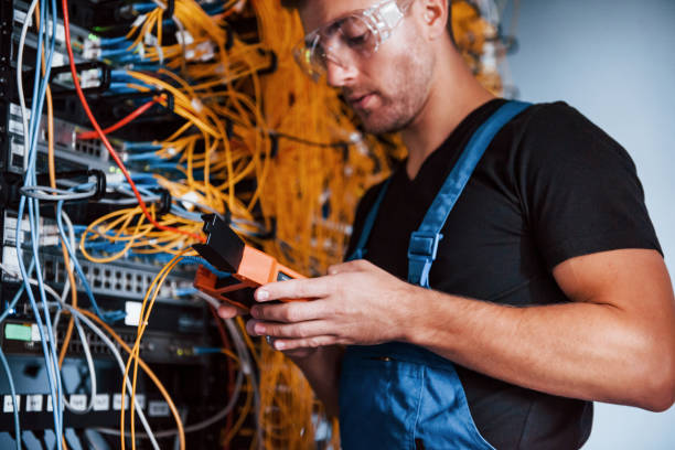 istock Young man in uniform with measuring device works with internet equipment and wires in server room 1310873163