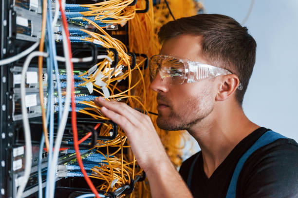 istock Young man in protective glasses works with internet equipment and wires in server room 1310873190