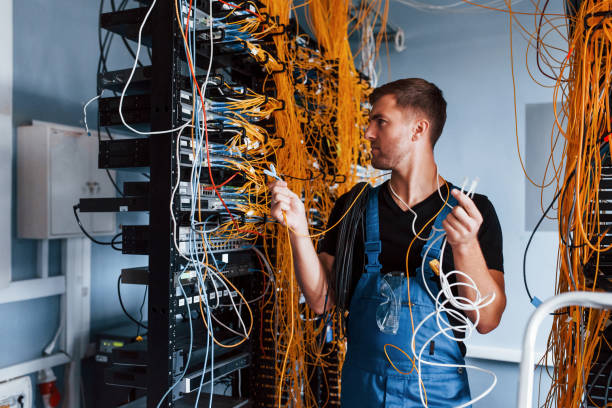 istock Young man in uniform feels confused and looking for a solution with internet equipment and wires in server room 1310873703