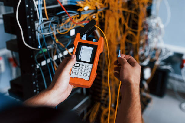 istock Young man withj measuring device in hands works with internet equipment and wires in server room 1310873735
