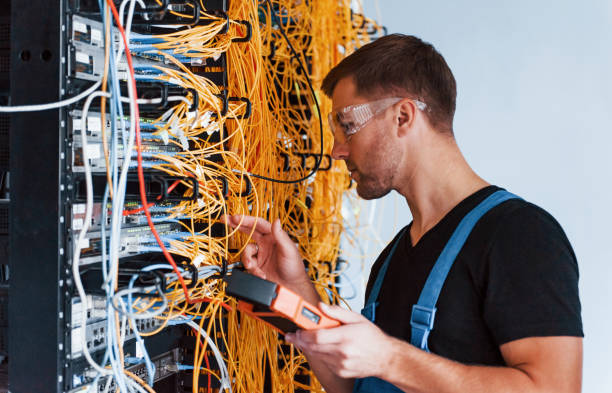 istock Young man in protective glasses works with internet equipment and wires in server room 1310873748
