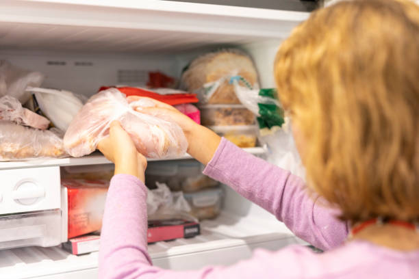 Teenager putting meat in a freezer stock photo