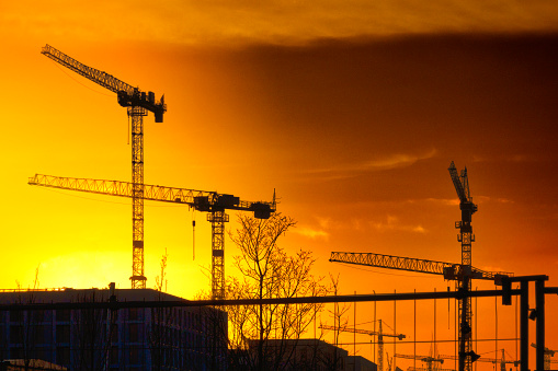 Construction site buildings and cranes in the backlight of the sunset