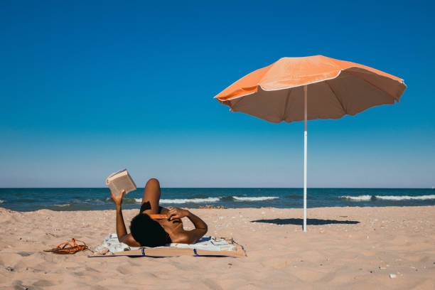 Mature woman reading a book from the terrace above the sea.