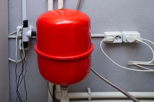 Red expansion tank and pipelines in the boiler room of a private house. High quality photo