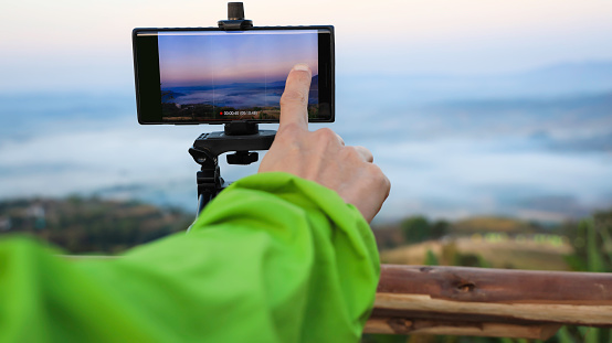Selective focus  Man  hand traveler blogger work remote which he is a recording of enjoying the nature landscape view in sunset sky scene background