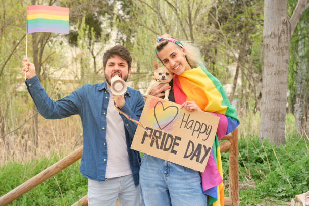 dois amigos e um cachorro lutando pela igualdade de gênero com um megafone e bandeiras de arco-íris. conceito de protesto lgbt. - lesbian love sexual issues two people - fotografias e filmes do acervo