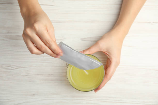 femme versant la poudre du sachet de médecine dans le verre avec l’eau à la table, vue supérieure - sachet photos et images de collection