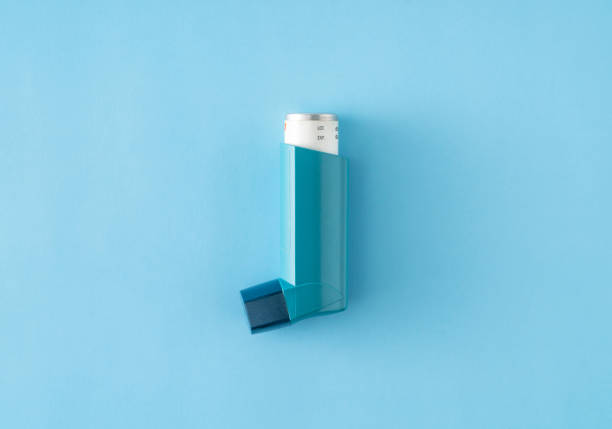 inhalador de asma sobre fondo azul - inhalador de asma fotografías e imágenes de stock