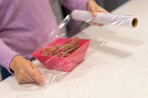Teenager covering a food bowl with cling film stock photo