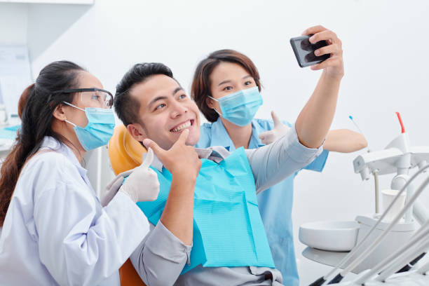 мужчина делает селфи со стоматологом и ассистентом - dentist asian ethnicity portrait male стоковые фото и изображения