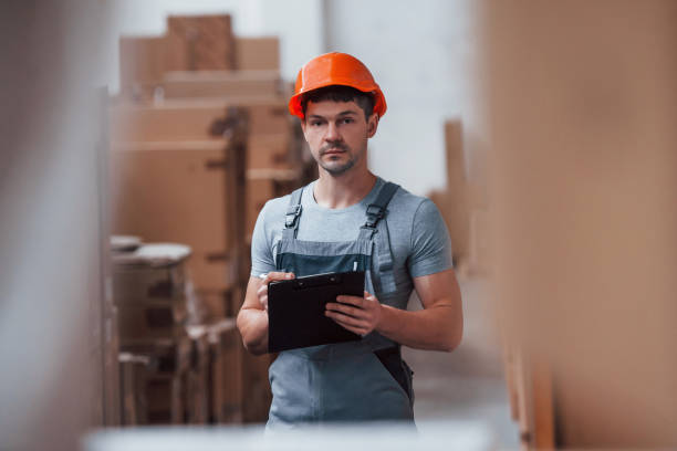 istock Storage worker in uniform and notepad in hands checks production 1310895928