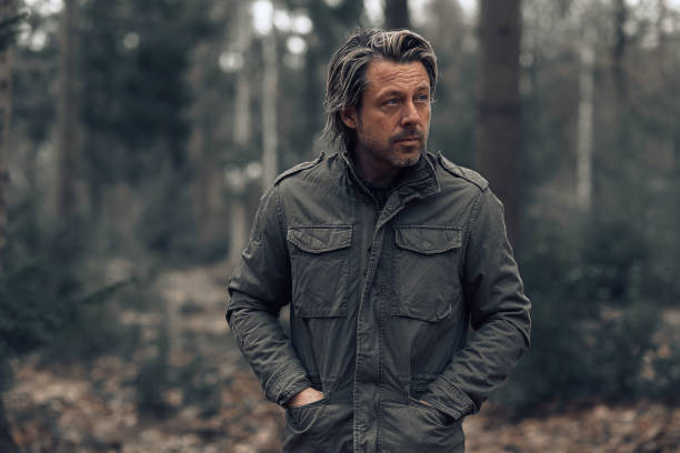 istock Cool blonde man in green coat walks in a forest. 1310895974