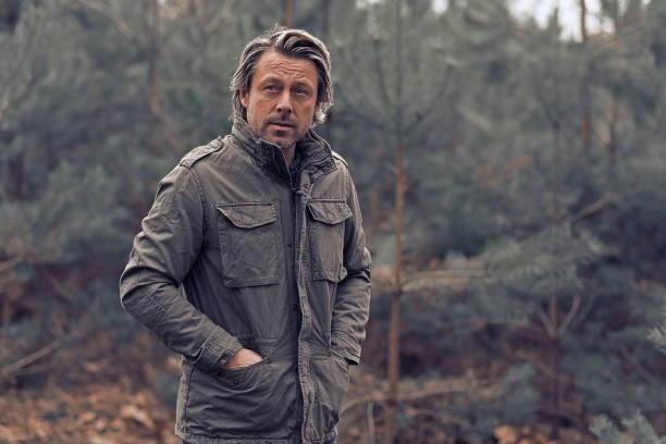 istock Cool blonde man in green coat walks in a forest. 1310895977