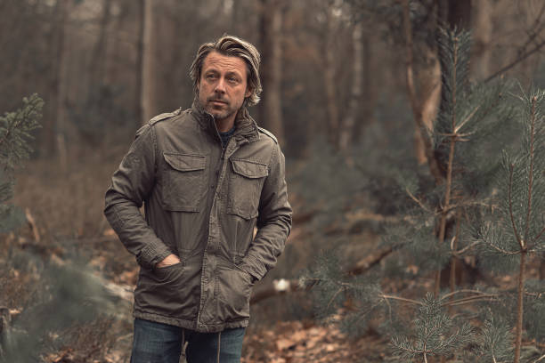 istock Cool blonde man in green coat walks in a forest. 1310895981