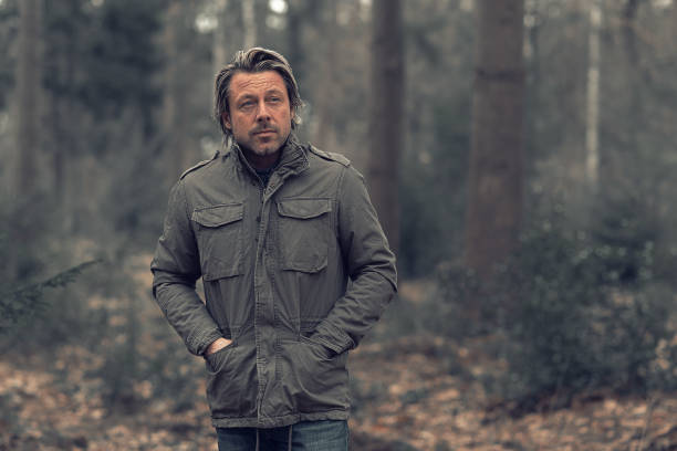 istock Cool blonde man in green coat walks in a forest. 1310895986
