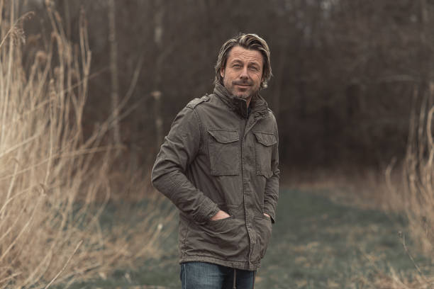 istock Cheerful blond man in green jacket on grassy path between tall reed in nature reserve. 1310896036