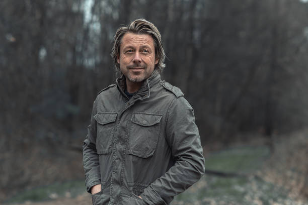 istock Smiling blond man in green coat in a nature reserve. 1310896039