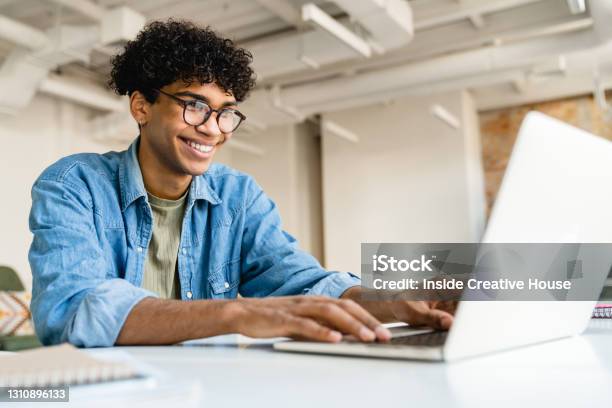 Gelukkige Glimlachende Afro Zakenman Die Laptop Met Behulp Van Bij Het Bureau In Bureau Stockfoto en meer beelden van Studerende