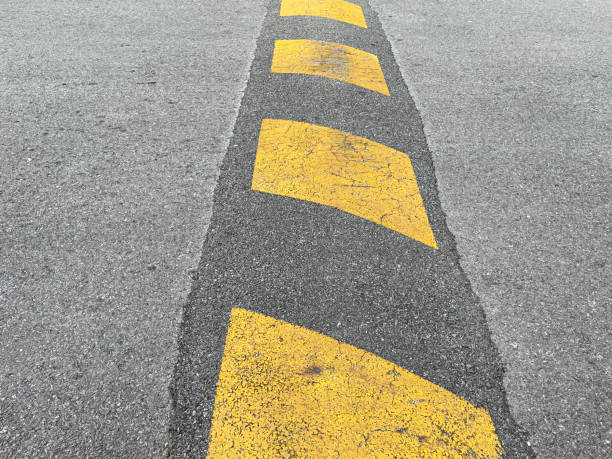 istock Vertical striped black and yellow asphalt speed hump and bump. 1310897377