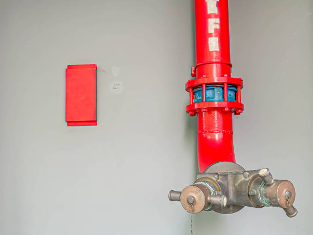 istock Fire department connection with gray concrete or cement wall and red label. 1310897409