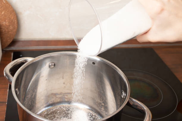 istock Women's hands pour sugar into a saucepan 1310897833