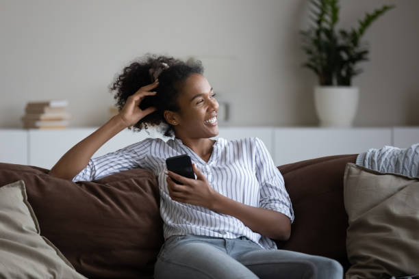 istock Smiling biracial woman relax on sofa using cellphone 1310898638