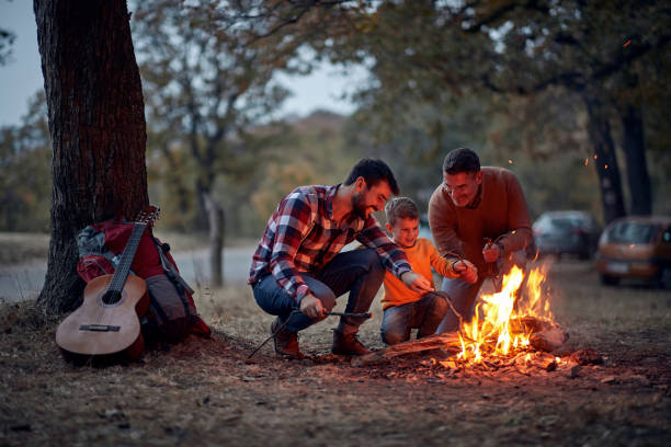 Child with dad and grandpa preparing campfire Male child with dad and grandpa in wood preparing campfire father and son guitar stock pictures, royalty-free photos & images