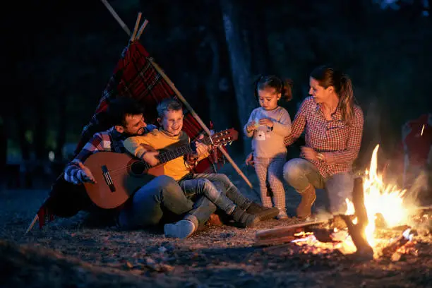 Family with children in the evening on camping near campfire