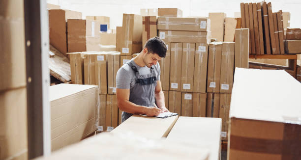istock Young male worker in uniform is in the warehouse with notepad and pen 1310901707
