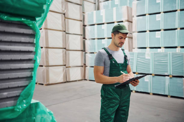 istock Storage worker in green colored uniform and notepad in hands checks production 1310901888