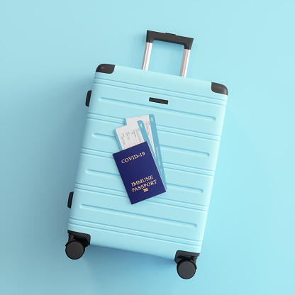 Covid-19 Vaccine Passport And Airplane Tickets On Blue Suitcase With Blue Background